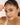 Woman holding a bracelet on her face with a plain background