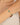 Gold bracelet with green beads on a wrist against a neutral background