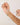 Hand holding a delicate gold necklace with green beads against a plain background