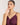 Woman wearing a purple dress and green necklace against a plain background