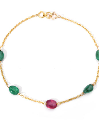 Gold bracelet with green and red gemstones on a white background