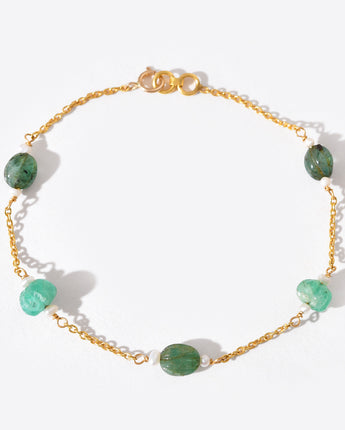 Gold bracelet with green gemstones on a white background