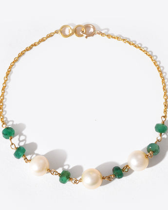 Bracelet with gold chain, green gemstones, and pearls on a white background