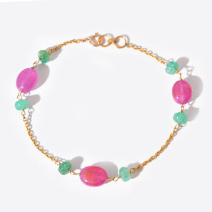Bracelet with pink and green beads on a gold chain against a white background