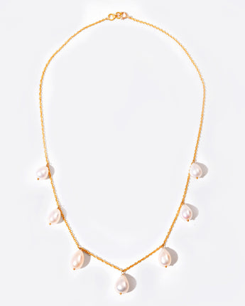 Gold necklace with pearl drops on a light background