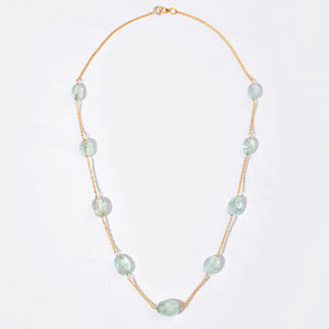 Necklace with white gemstone on a gold chain against a white background