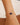 Gold bracelet with a blue gemstone and pearl on a wrist against a neutral background