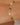 Gold bracelet with green gemstones and pearls on a wrist against a beige background