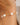 Gold bracelet with pearls on a wrist against a neutral background