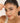Woman holding a bracelet on her face with a plain background