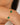 Gold bracelet with green stones on a wrist against a neutral background