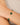 Gold bracelet with green gemstones on a wrist against a neutral background