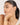 Woman touching her face wearing a delicate bracelet with a neutral background