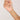 Hand holding a delicate gold necklace with small colored beads against a plain background