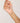 Hand holding a delicate gold necklace with small colored beads against a plain background