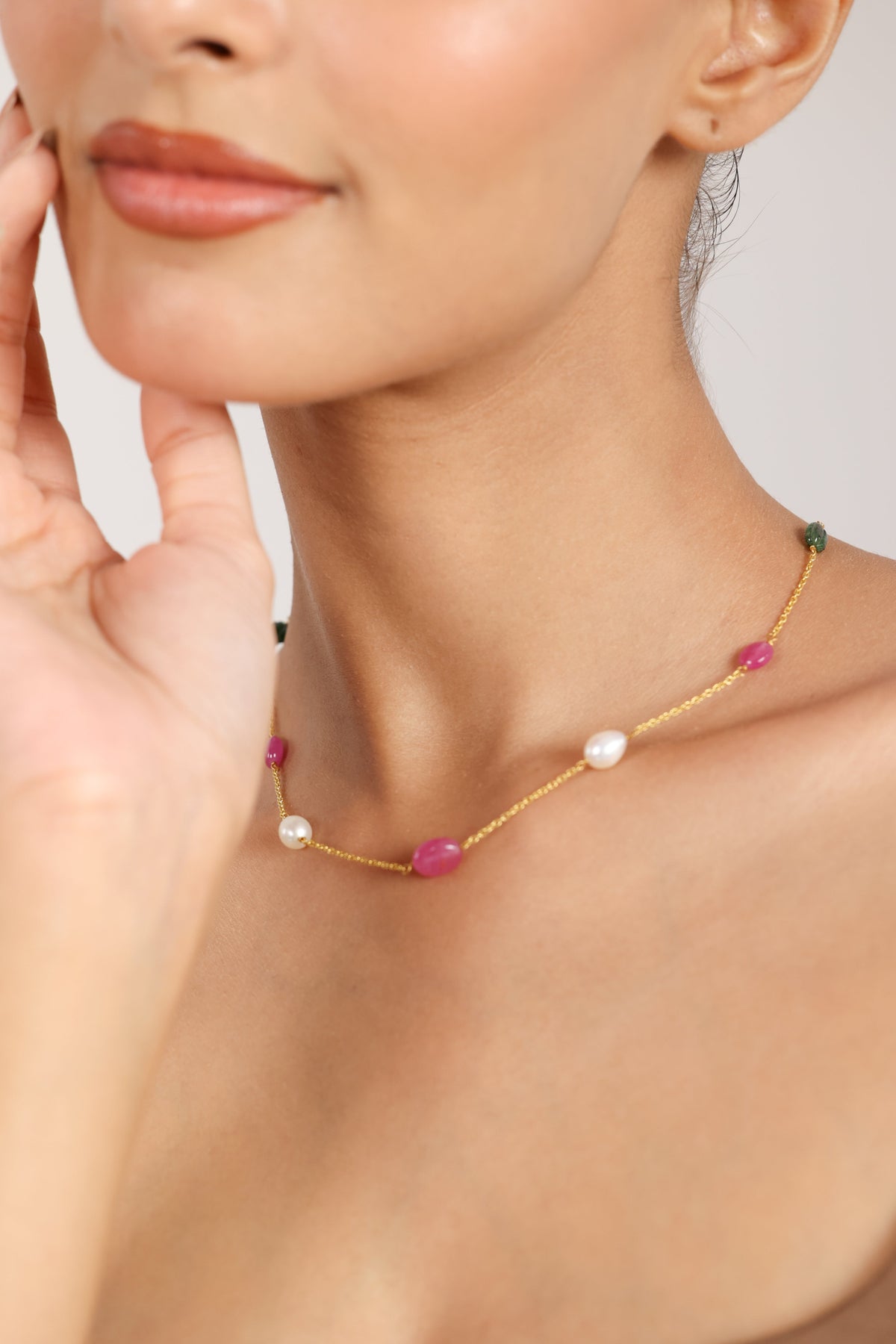 Necklace with pink and white beads worn by a woman on a neutral background