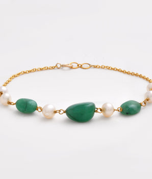 Bracelet with green stones and pearls on a gold chain against a white background