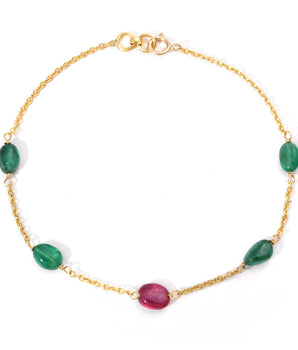 Gold bracelet with green and red gemstones on a white background