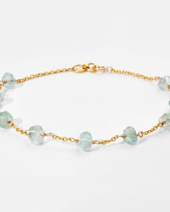 Gold bracelet with white gemstones on a light gray background