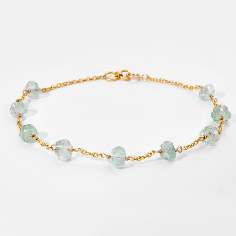 Gold bracelet with white gemstones on a light gray background