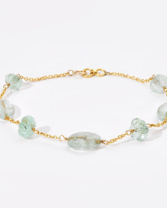 Gold bracelet with green gemstones on a white background