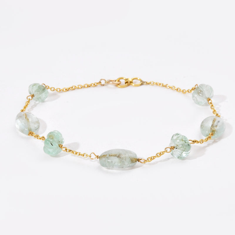 Gold bracelet with green gemstones on a white background