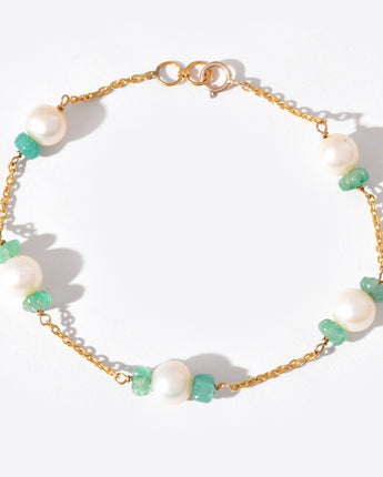 Gold bracelet with pearls and green beads on a white background