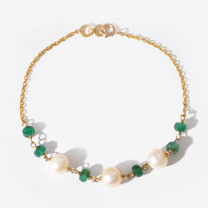 Bracelet with gold chain, green gemstones, and pearls on a white background