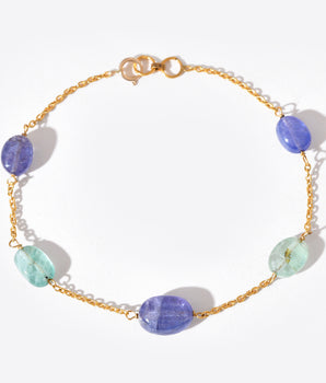 Bracelet with gold chain and multicolored beads on a white background
