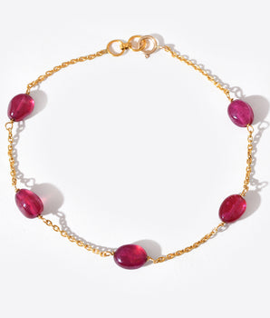 Gold bracelet with red gemstones on a white background