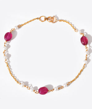 Bracelet with gold chain, white beads and pink stones on a white background