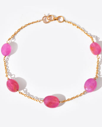 Bracelet with pink beads and gold chain on a white background