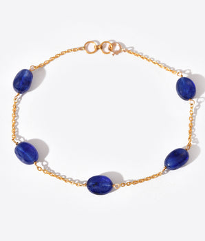 Gold bracelet with blue gemstones on a white background