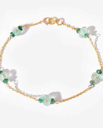 Gold bracelet with green gemstones on a white background