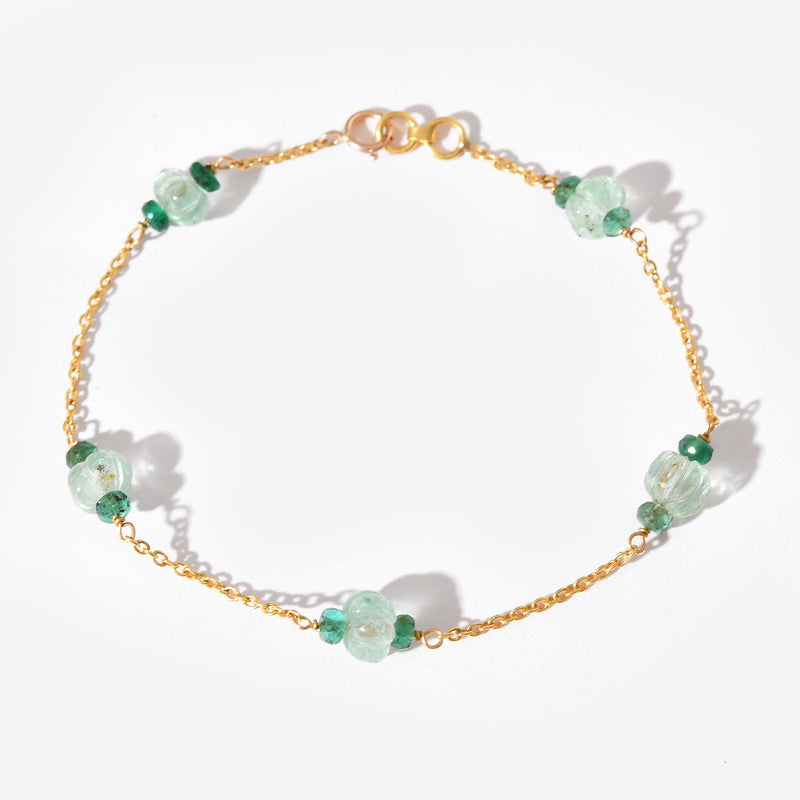 Gold bracelet with green gemstones on a white background