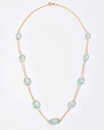Necklace with white gemstone on a gold chain against a white background